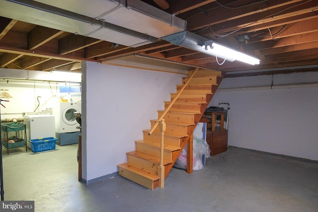 unfinished below grade area with stairway, washing machine and dryer, and concrete block wall