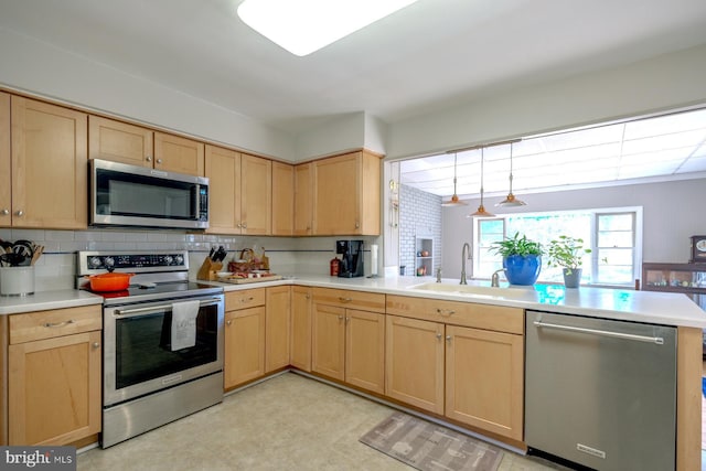 kitchen featuring a sink, appliances with stainless steel finishes, a peninsula, and light brown cabinetry