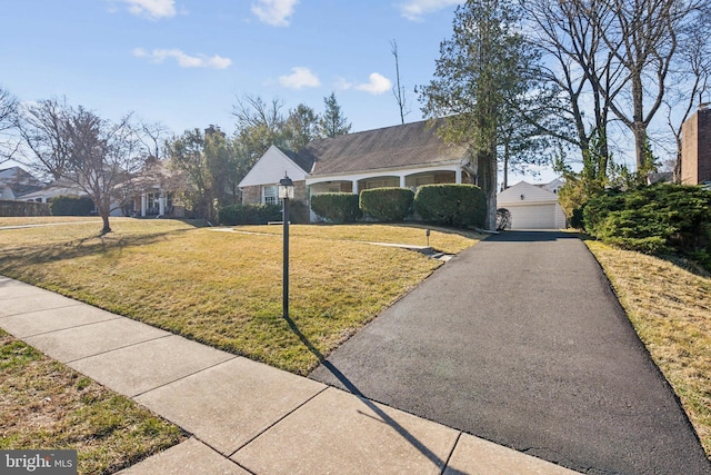 view of front of home with a front lawn, an outbuilding, and a garage