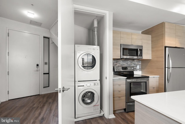 kitchen with light brown cabinets, dark wood finished floors, light countertops, stacked washer and clothes dryer, and appliances with stainless steel finishes