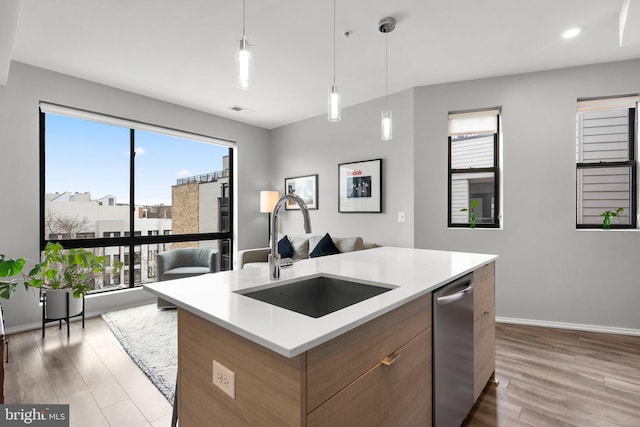 kitchen featuring a sink, dishwasher, wood finished floors, and light countertops