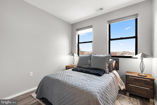 bedroom featuring visible vents, baseboards, and wood finished floors