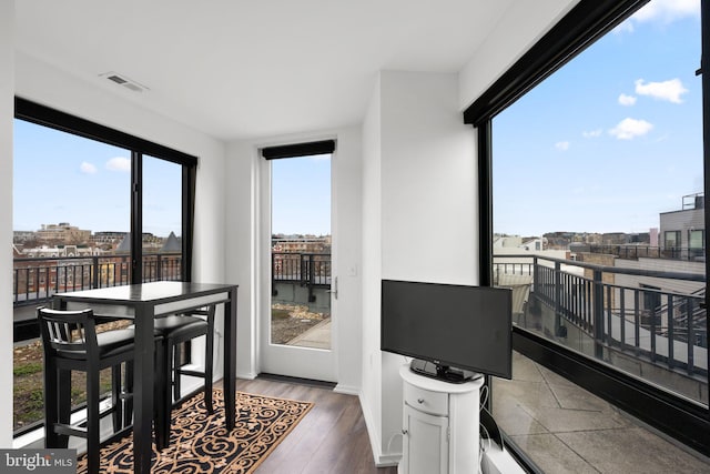 dining space with a view of city, wood finished floors, visible vents, and baseboards