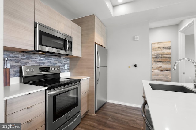 kitchen with appliances with stainless steel finishes, modern cabinets, light countertops, and a sink