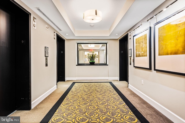 hallway with carpet, elevator, a raised ceiling, and baseboards