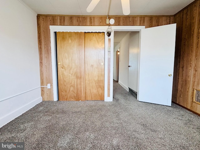 unfurnished bedroom featuring crown molding, a closet, wood walls, and carpet floors