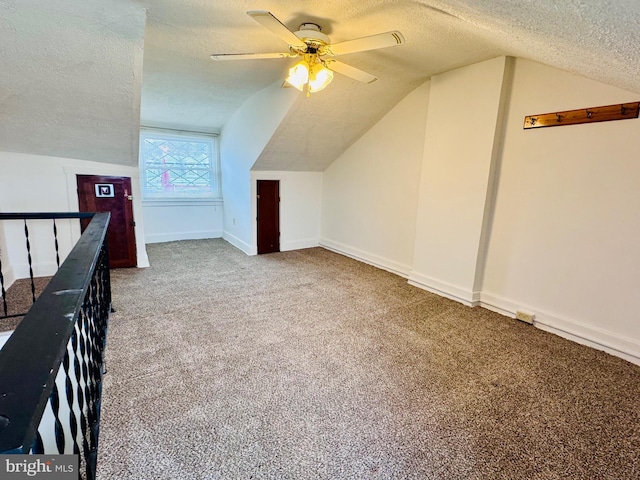 additional living space featuring a ceiling fan, carpet, baseboards, vaulted ceiling, and a textured ceiling