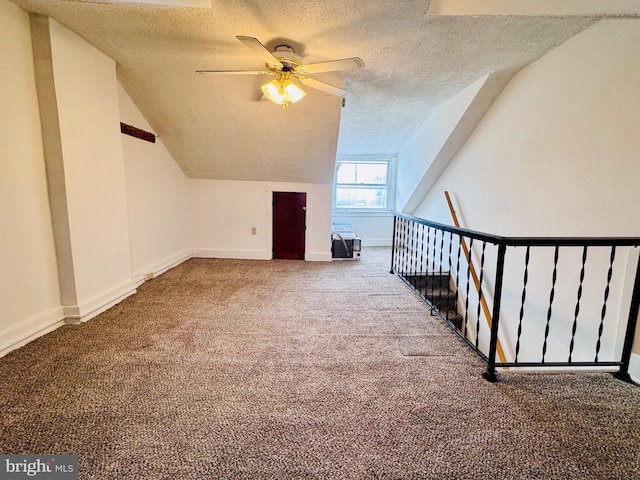 additional living space featuring baseboards, ceiling fan, vaulted ceiling, carpet floors, and a textured ceiling