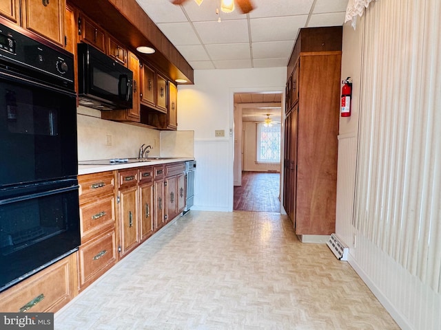 kitchen featuring black appliances, a paneled ceiling, light countertops, and ceiling fan