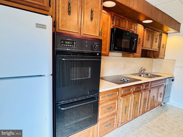 kitchen featuring black appliances, light countertops, brown cabinets, and a sink