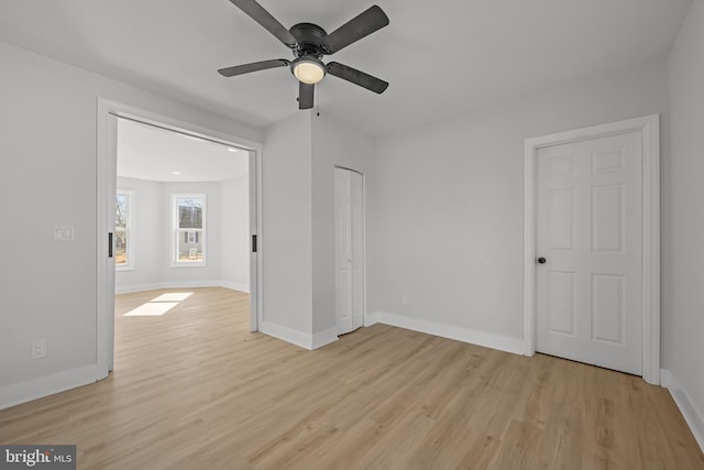 interior space featuring a ceiling fan, light wood-style flooring, and baseboards