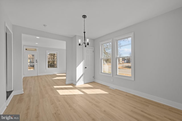 unfurnished dining area featuring light wood-type flooring, baseboards, visible vents, and a chandelier