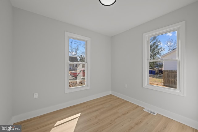 spare room featuring visible vents, light wood-style flooring, and baseboards