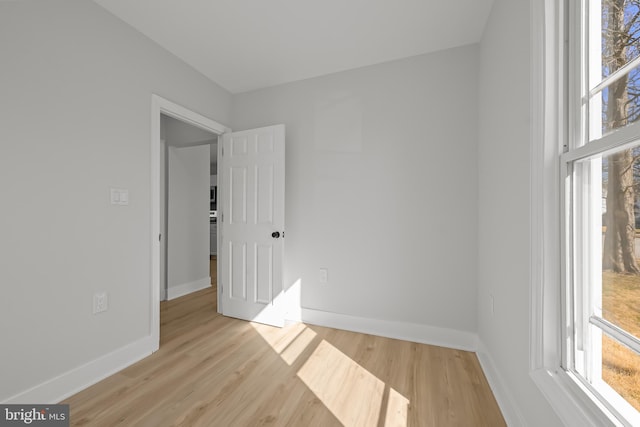 empty room with a healthy amount of sunlight, baseboards, and wood finished floors