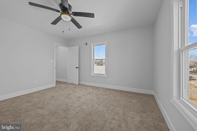 carpeted empty room featuring visible vents, ceiling fan, and baseboards