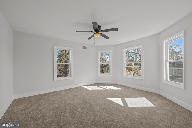 carpeted empty room featuring ceiling fan, visible vents, and baseboards