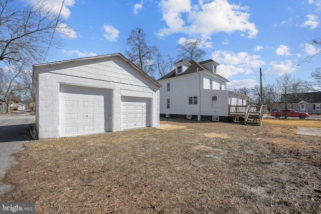 view of home's exterior with a garage, a wooden deck, and an outdoor structure