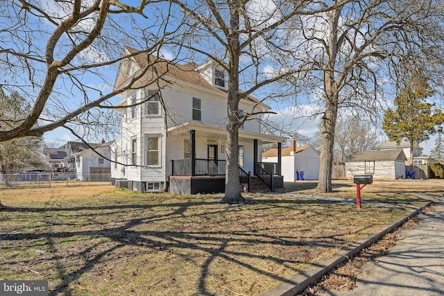 american foursquare style home with covered porch, fence, a front lawn, and central AC