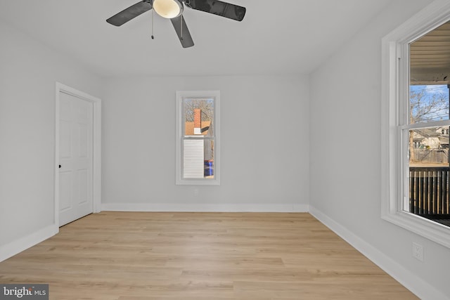 spare room featuring ceiling fan, light wood-style flooring, and baseboards