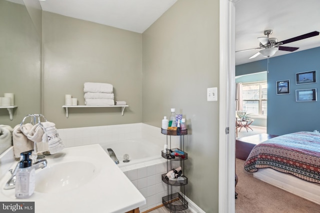 bathroom featuring a garden tub, baseboards, ceiling fan, and a sink