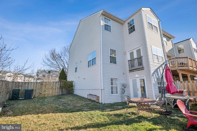 rear view of house featuring a lawn, a fenced backyard, and a gate