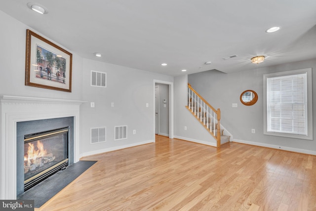 unfurnished living room featuring visible vents, wood finished floors, and stairway