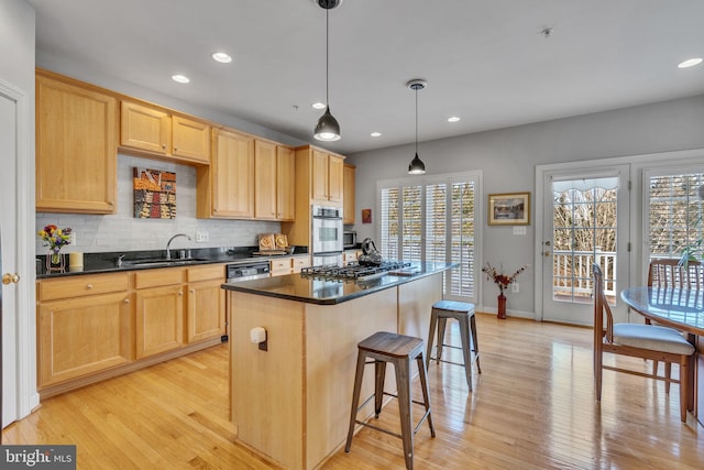 kitchen featuring light brown cabinetry, a kitchen breakfast bar, dark countertops, and a sink