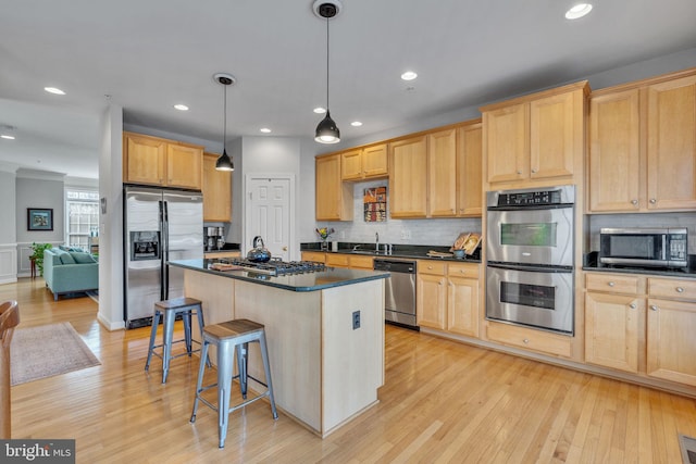 kitchen featuring light brown cabinets, a kitchen breakfast bar, dark countertops, tasteful backsplash, and stainless steel appliances