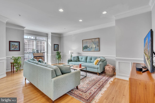 living room featuring crown molding, a decorative wall, recessed lighting, and light wood finished floors