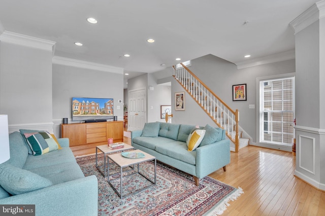 living room with stairs, crown molding, and light wood-type flooring