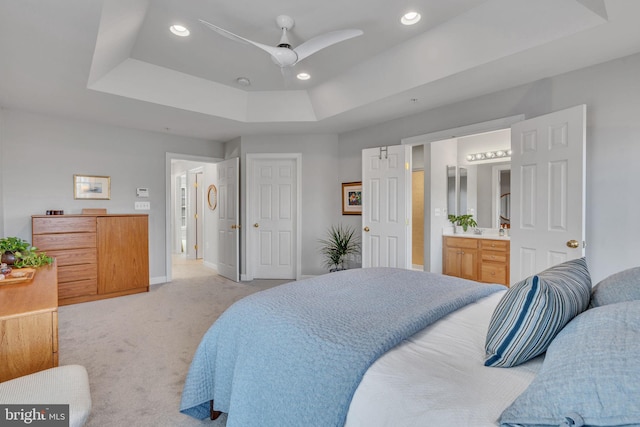 bedroom featuring recessed lighting, a tray ceiling, light carpet, and ensuite bath