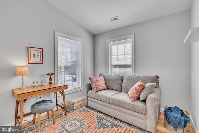 living room featuring visible vents, lofted ceiling, baseboards, and wood finished floors