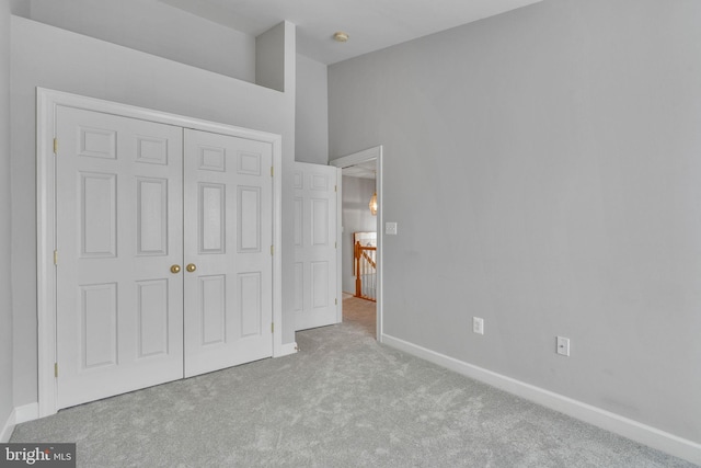 unfurnished bedroom with carpet, a closet, and baseboards