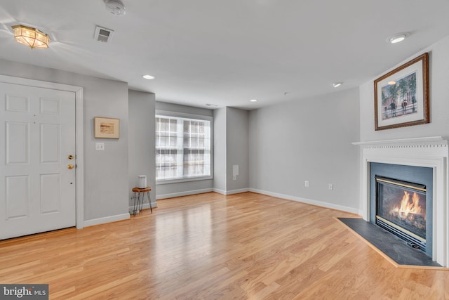 unfurnished living room featuring visible vents, a fireplace with flush hearth, baseboards, and light wood-style flooring