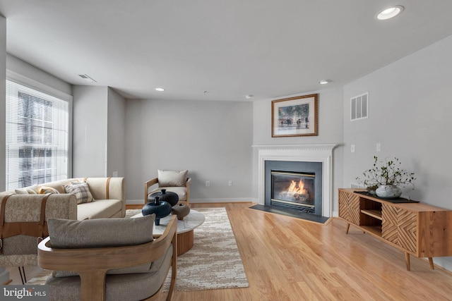 living area with recessed lighting, visible vents, baseboards, and wood finished floors