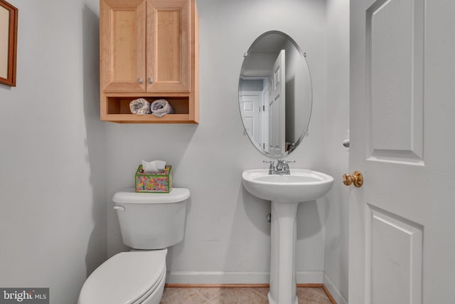 bathroom with toilet, baseboards, and a sink