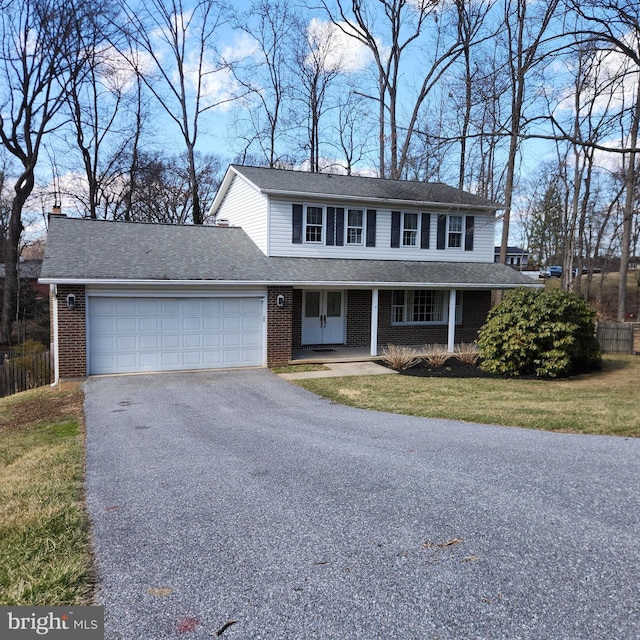 view of front of house with driveway, covered porch, a front lawn, a garage, and brick siding