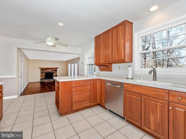 kitchen with a sink, stainless steel dishwasher, a healthy amount of sunlight, and a fireplace