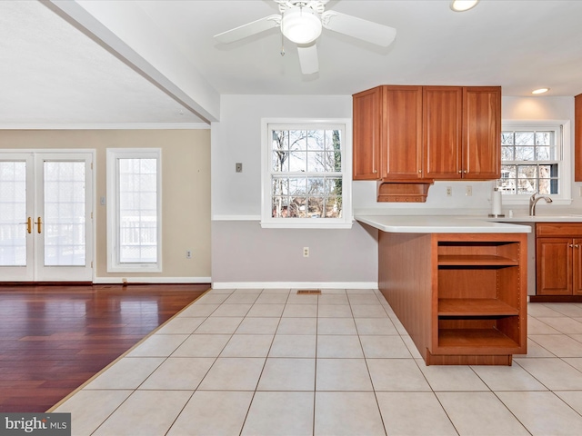 kitchen featuring open shelves, baseboards, brown cabinets, and light countertops