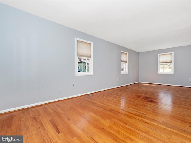 unfurnished room with light wood-type flooring, baseboards, and visible vents