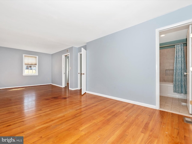 unfurnished room featuring visible vents, light wood-style floors, and baseboards