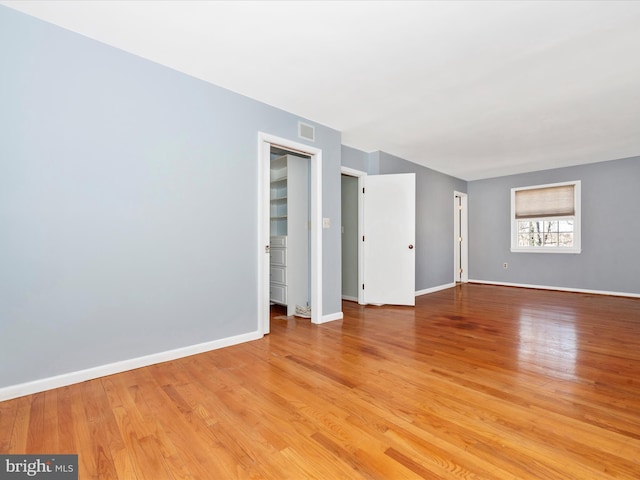 spare room featuring visible vents, light wood-style flooring, and baseboards