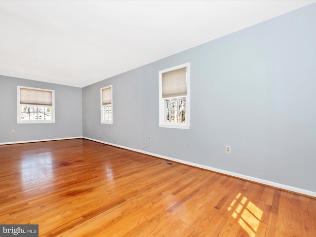 empty room featuring visible vents, baseboards, and light wood finished floors