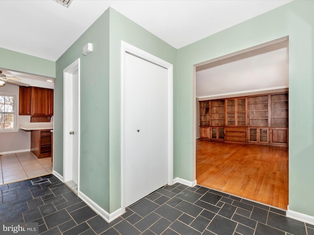 hall featuring dark tile patterned floors and baseboards