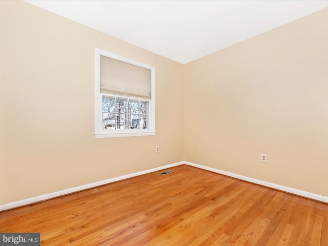 empty room with visible vents, baseboards, and wood finished floors