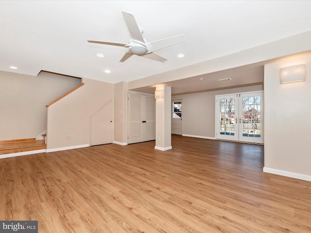 unfurnished living room featuring stairs, baseboards, and light wood finished floors