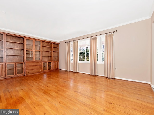 unfurnished living room featuring baseboards, light wood finished floors, and ornamental molding