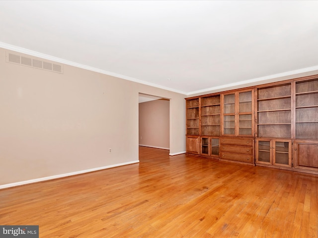 spare room with visible vents, baseboards, ornamental molding, and light wood finished floors