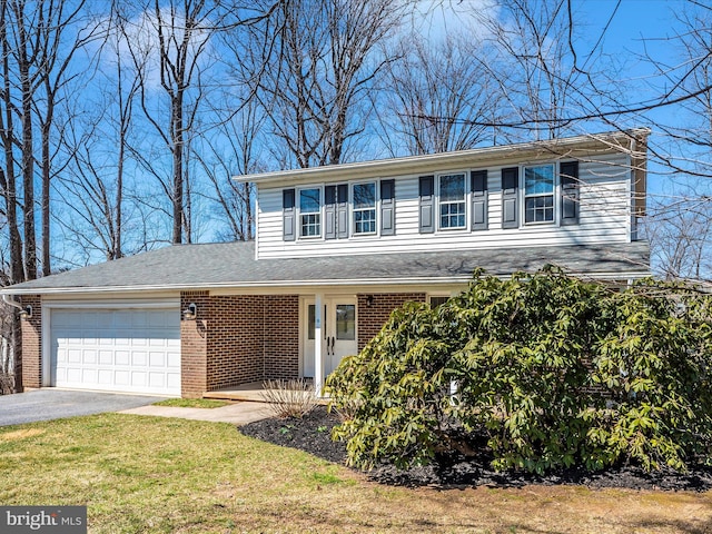 traditional-style house featuring brick siding, an attached garage, aphalt driveway, and a front yard