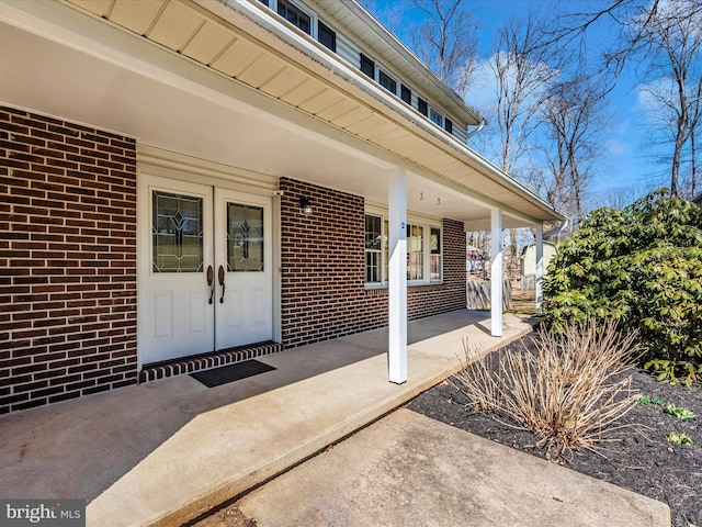 property entrance featuring brick siding and a porch